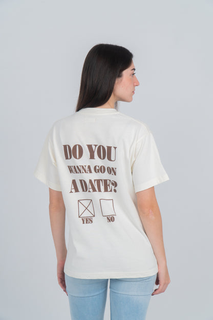 Chica viste camiseta/Tee beige con diseño en la espalda que pone Do you wanna go on a date? y dos cuadros uno de ellos tachados con una cruz, donde pone yes. El otro cuadro pone no. 